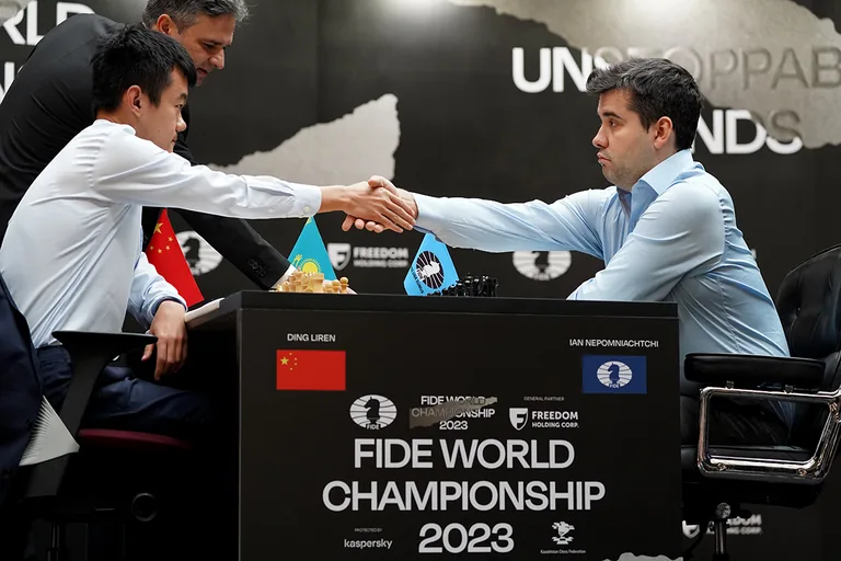 Ding Liren and Ian Nepomniachtchi shake hands across the board during the 2023 World Championship rapid playoff.